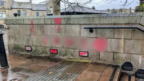 Blurred photo showing antisemitic graffiti sprayed on a wall in Glossop
