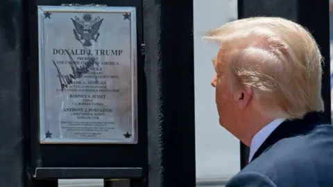 Getty Images President Trump inspects a section of wall with a signed plaque on it