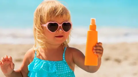 Getty Images Child on the beach with suncream