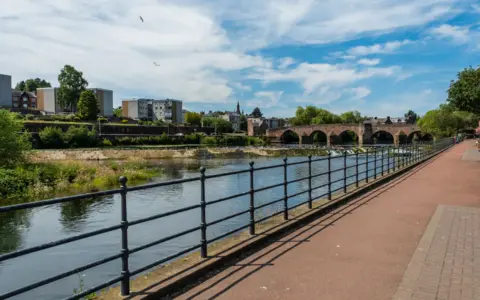 Getty Images A view across the River Nith in Dumfries with railings in front of it and a sandstone bridge crossing the top of it