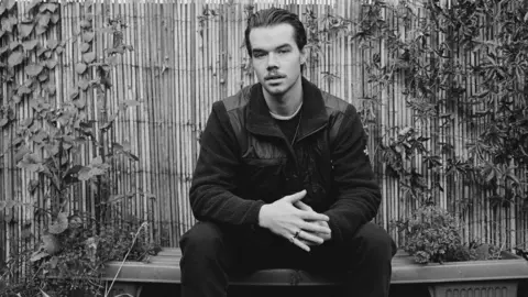 Ale X Kurunis Musician Oscar Jerome sitting down in a garden