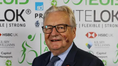 Getty Images Lord Dafydd Elis-Thomas, deputy Minister for Culture, Sport and Tourism during the Welsh Cycling awards at Sophia Gardens on October 12, 2019 in Cardiff, Wales. He is wearing a black suit, blue shirt and navy tie and black glasses.