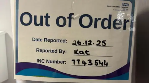 Sarah Cadwallader Out of order NHS sign indicating problem was reported on 26 December by a worker called Kat and a case number.