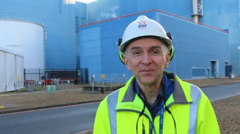 George King/BBC Robert Gunn wearing a hard hat and high vis jacket smiling into the camera