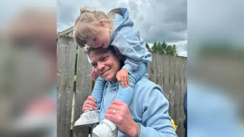 Adam Barnes Amelia Barnes riding on the shoulders of her father, Adam, both are smiling