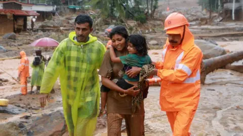 Reuters Rescuers help residents to move to a safer place, at a landslide site after multiple landslides in the hills, in Wayanad, in the southern state of Kerala, India, July 30, 2024. REUTERS/Stringer