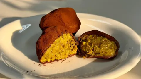 A Dubai chewy cookie cut in half on a plate, showing its pistachio green filling