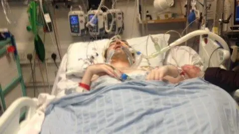 Handout a man lies seriously ill in a hospital bed, connected to breathing tubes and other machines