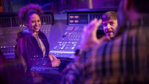 A woman and man sitting in a recording studio 