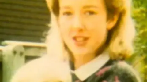 Undated image of the late Diane Sindall, who has blonde hair, smiles at the camera while holding a light coloured puppy which appears to be a labrador