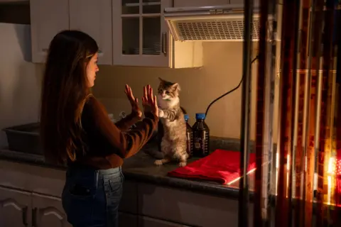 Fritz Pinnow Lucía Ramírez high fives her cat Toto while waiting for the film to react with the chemicals..