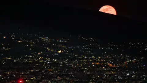 EPA The red supermoon rises behind Mt Vesuvius as seen from Naples, Italy