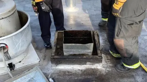 Alameda County Sheriff Firefighters contemplate how best to remove the man from the rooftop vent