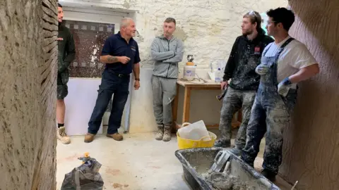 workmen applying plaster to a wall