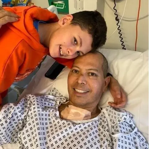 PA Media Mr Franco posing with his son Gabriel while he recovers in a hospital bed.