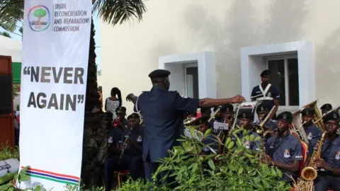 AFP A band playing at the launch of the TRRC next to a banner saying, "Never again" - October 2018