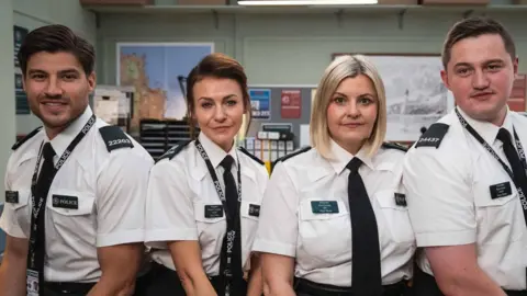 BBC/Long Story TV Four actors from Hope Street. A man with dark hair and a beard, white shirt and black tie, a woman with brown hair a white blouse and dark tie, a woman with blonde hair a white blouse and black tie, and a man (Finnian Garbutt) with dark hair, wearing a white shirt and black tie.