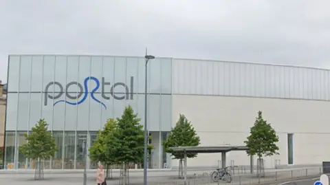 Google A large leisure centre building, with PORTAL written in grey and blue letters. Several trees sit on the street outside the building. 