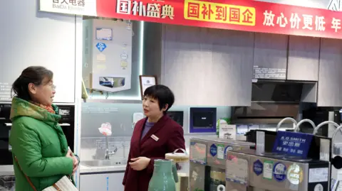 Customer selects home appliances as a poster promoting trade-in subsidy policy is seen at a market in China.