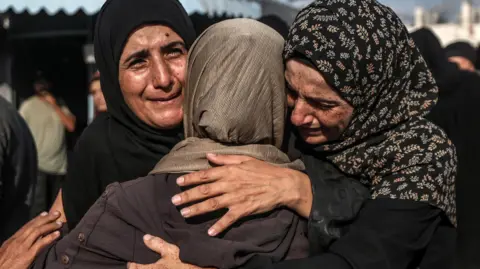 EPA A group of relatives mourn during the funeral of Palestinians killed in an Israeli airstrike in Deir Al-Balah in Gaza on 6 October