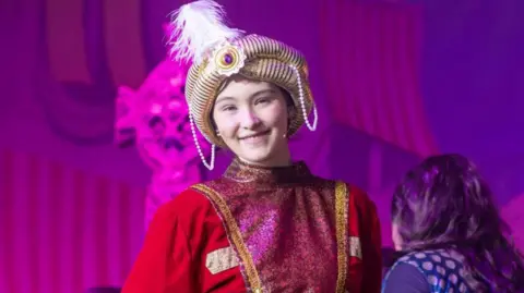 WithYou A young woman with a hat on with a feather in it and a red jacket