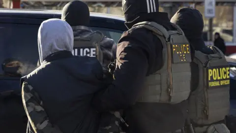 A Federal Agent arrest a man after stopping and questioning him in the street during an Immigration Enforcement Operation in Minneapolis, Minneapolis, MN, U.S., January 14, 2026. 