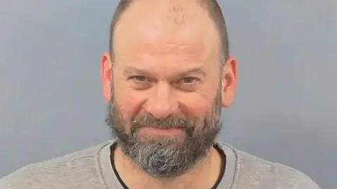 Barnaby Money with a grey beard and a grey sweat-shirt in a custody image.