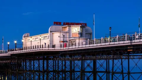 An old Victorian pier at dusk being lit by a pink light as the sun sets. 