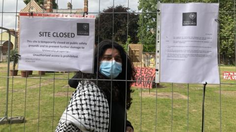 Demonstrator behind newly-erected fencing outside National History Museum wearing face mask