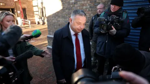 Reuters/Phil Noble Suspended Labour MP Mike Amesbury walks past members of the media, outside Chester Magistrates Court in January. He is wearing a red tie and looks glum.