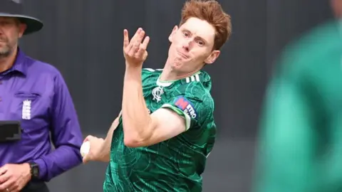 James Hayes is bowling a ball while playing in the green shirt of Nottinghamshire.