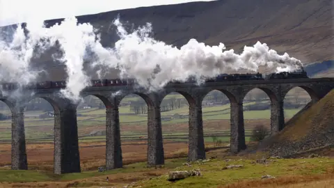 A steam train travels over a 30-metre tall viaduct in the countryside