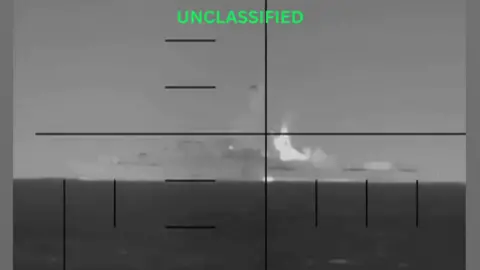 A black and white image of a ship through a scope