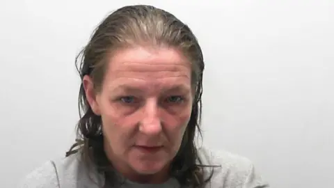 North Yorkshire Police Custody picture of a woman with a wrinkled forehead and shoulder-length hair.