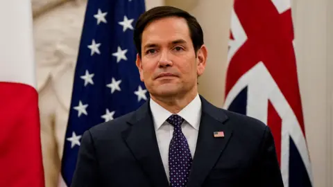 U.S. Secretary of State Marco Rubio wearing a black suit with a white shirt and a printed tie in Washington in 2025