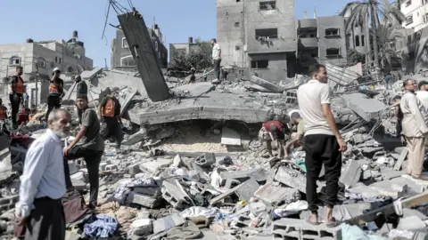 EPA Palestinians search for victims and survivors in the rubble of a residential building levelled in an Israeli airstrike in Khan Younis refugee camp in the southern Gaza Strip.