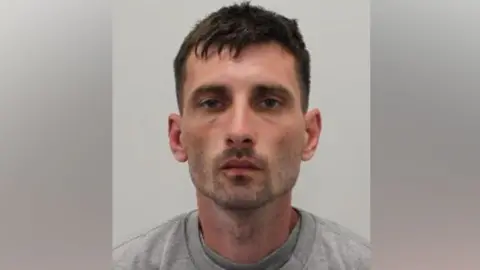 A man with brown hair and a short beard