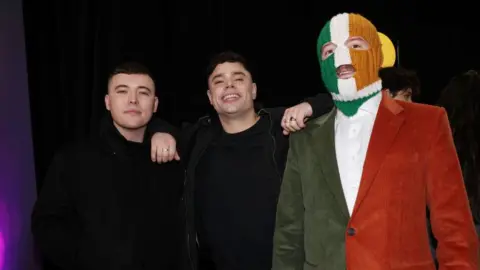 Kneecap members Mo Chara, Moglai Bap and DJ Provai standing together.