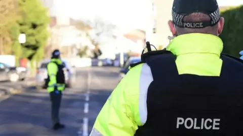 Pacemaker Show a female police officer on the left and a male officer on the right, both in high-visability vests and flak jackets. Their faces cannot be seen. 