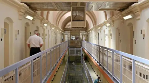 A shot of a prison officer walking along inside a prison