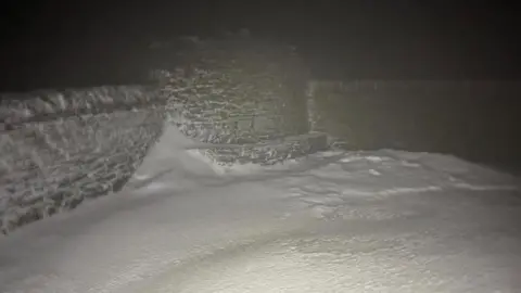 Anna Troup A snow drift atop of Cross Fell in the dark. The conditions look very cold and it is lit up by a torch.
