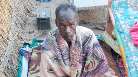 Mohamed Suleiman Mohamed Suleiman looks up at the camera, he has a blanket around his shoulders.