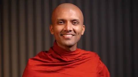 Mahindasiri Thero Picture of The Ven Mahindasiri Thero wearing a blood orange robe.