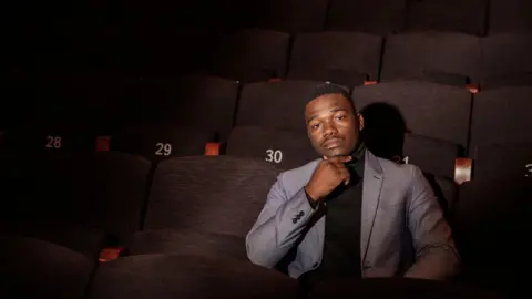 Gianluigi Guercia/ AFP Lulama Taifasi sitting in a darkened theatre looking reflective. Picture taken 5 June.