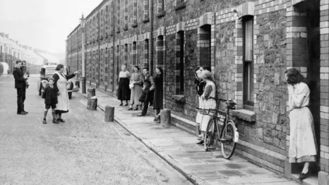 Getty Images A black and white old image of some old residents of Llewellyn Street in Port Talbot outside their terraced houses