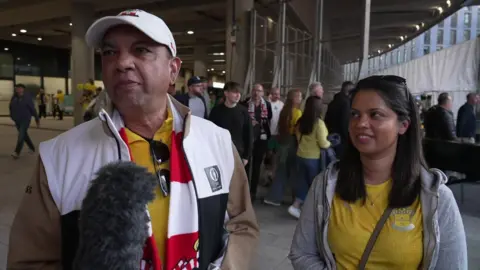 A man and a woman giving an interview after the Saints game at Wembley. They are wearing the team colours.