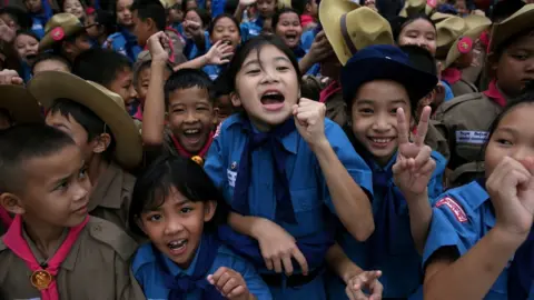 Reuters Students celebrate in front of Chiang Rai Prachanukroh hospital, where the 12 soccer players and their coach rescued from the Tham Luang cave complex are being treated, 11 July 2018