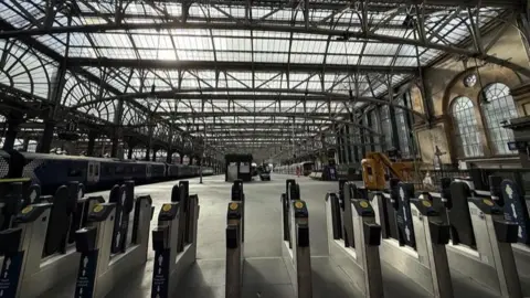 The inside of Glasgow Central Station showing train platforms and ticket barriers.