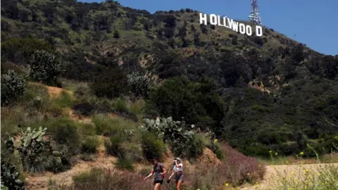 Reuters People hike beneath the Hollywood sign after a partial reopening of Los Angeles hiking trails during the outbreak of the coronavirus disease
