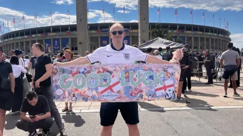 SS Peter and Paul Catholic Primary School vice principal Jamie Morgan holding the banner outside the stadium in Berlin